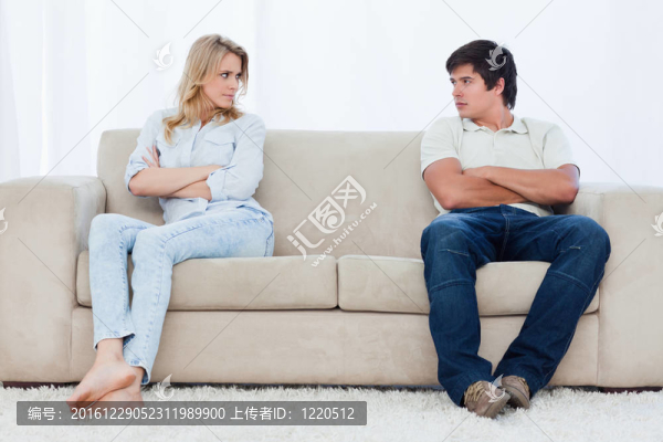 一對(duì)夫婦坐在沙發(fā)的兩端，雙臂交叉
