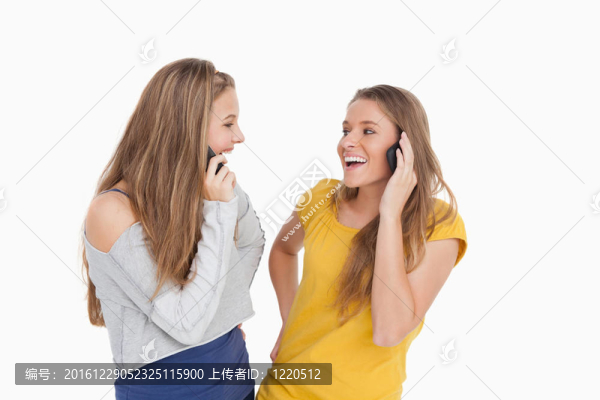 兩個年輕女人在電話上一起笑