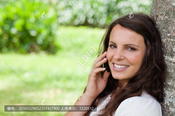 年輕的微笑的女人在看電話的時候說話