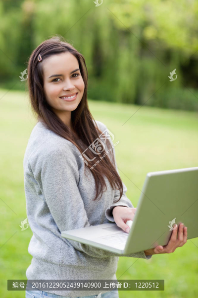 年輕的面帶微笑的女人拿著筆記本站著
