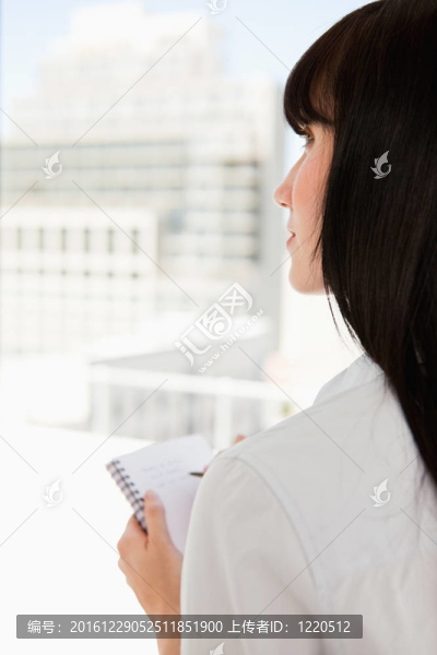 靠近一個(gè)女人凝視著上方，手里拿著一個(gè)記事本