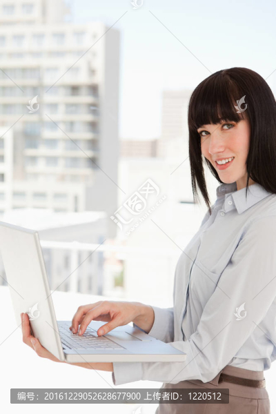 一個(gè)女人拿著筆記本看著相機(jī)