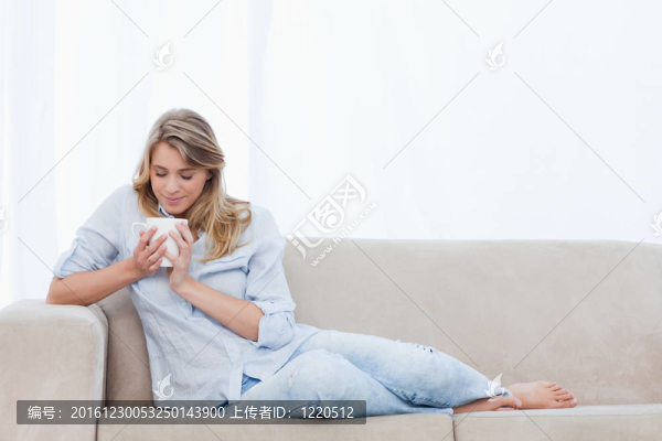 一個女人正在聞著她手里拿著的一杯咖啡