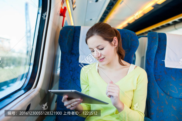 年輕女子坐火車旅行時使用平板電腦