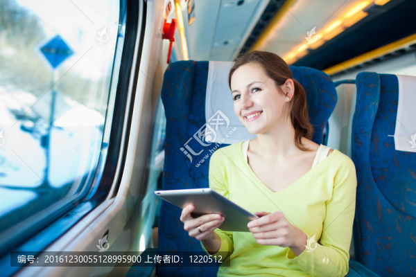 年輕女子坐火車旅行時使用平板電腦
