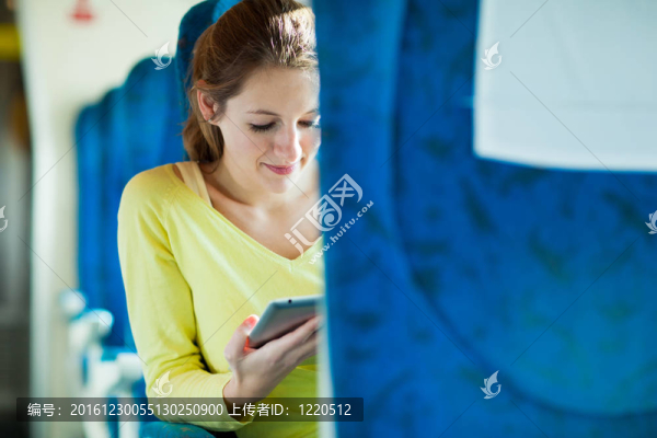 年輕女子坐火車旅行時使用平板電腦