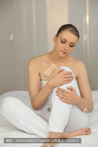 穿著白色衣服的女人坐在白色的床上