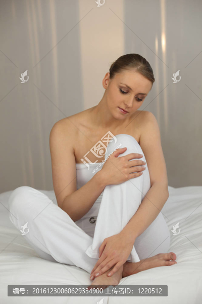 安靜的年輕女子坐在白色的床上