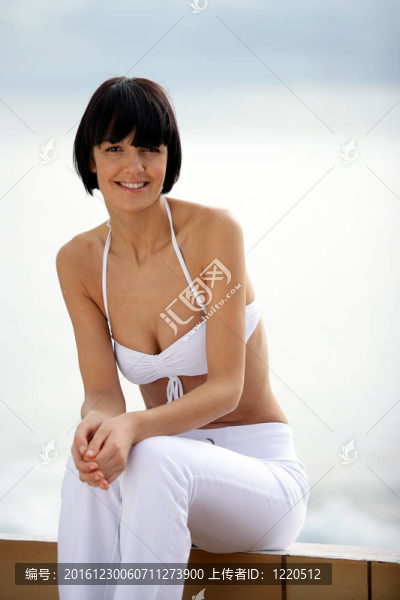 黑發(fā)女人坐在墻的海灘