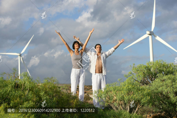 在風力渦輪機附近伸展的男人和女人