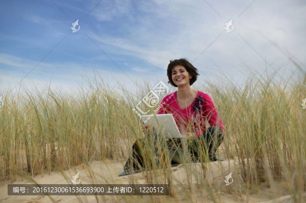 在沙丘中使用筆記本電腦的婦女