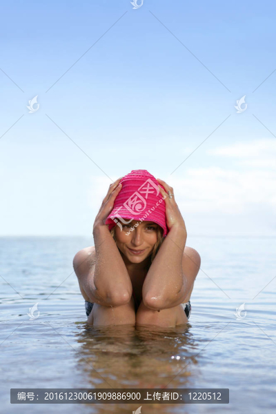 戴著帽子的女人坐在海里