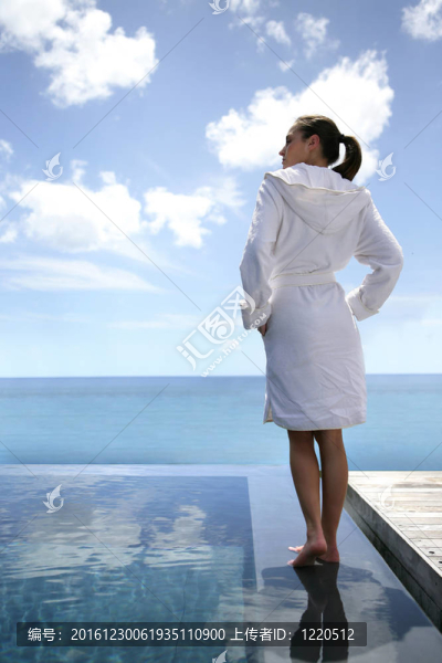 女子站在游泳池的浴袍
