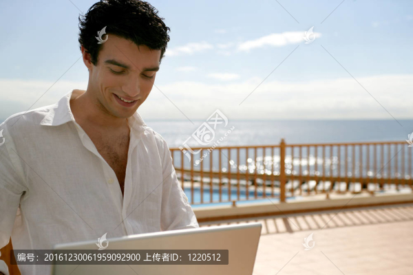 男子在泳池旁的陽(yáng)臺(tái)上使用筆記本電腦