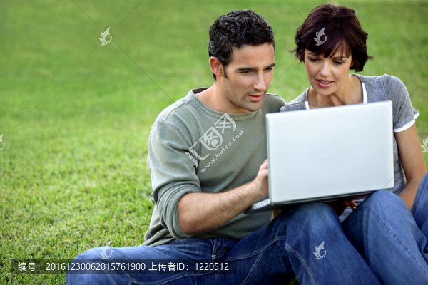 男人和女人在草地上與筆記本電腦