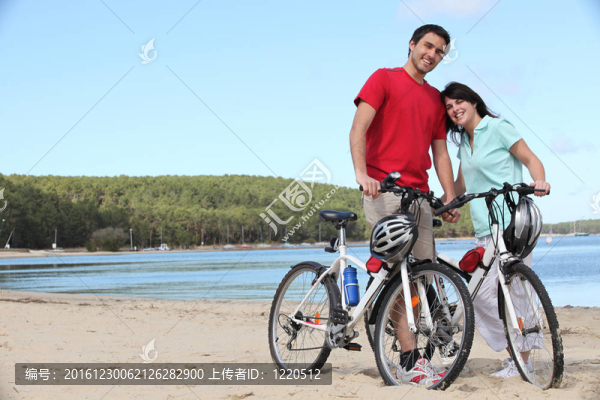在海灘上騎自行車的年輕夫婦