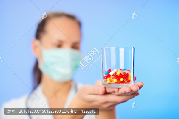 藥片和藥片在醫(yī)生的手上堆積在藍(lán)色的背景上