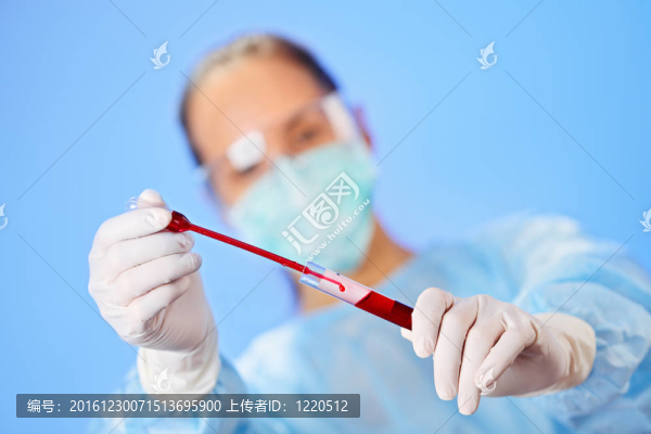 年輕的女醫(yī)生在藍(lán)色試管和滴管使血液分析