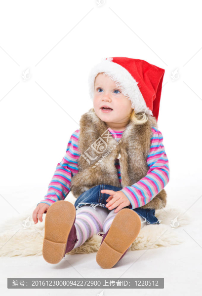 一個穿著毛皮夾克和紅Santa帽子的金發(fā)女孩坐在地板上