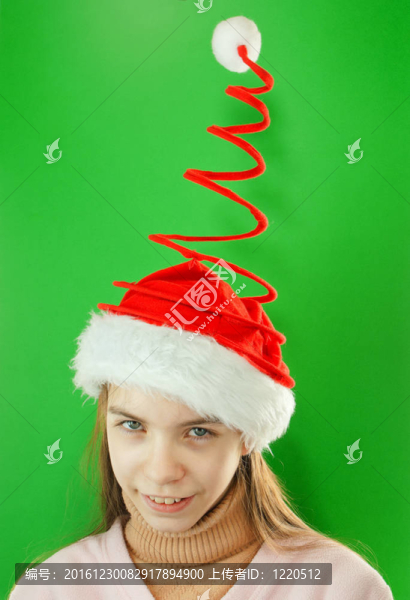 漂亮的Santa女孩；一個女孩戴著圣誕帽在綠色背景的特寫肖像