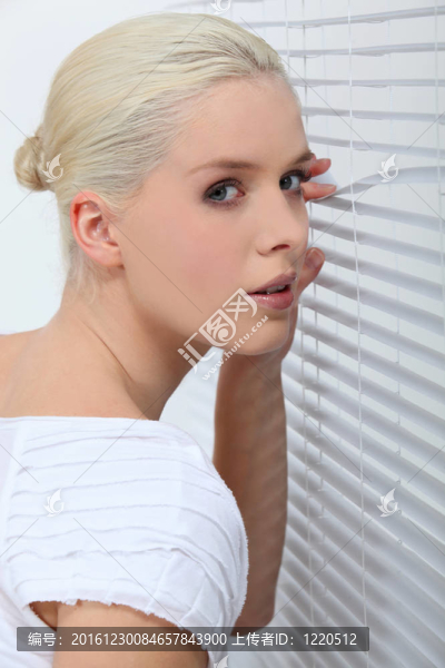 女人透過百葉窗窺視