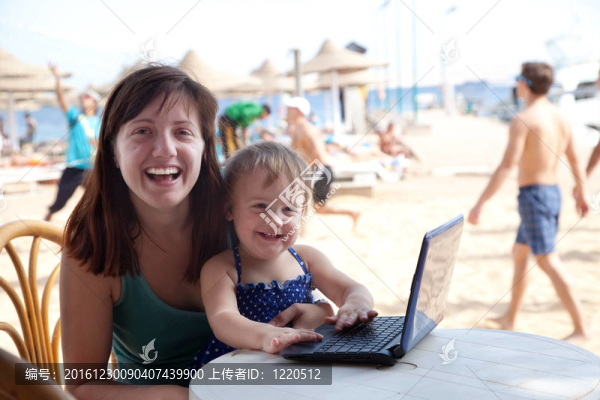 快樂的媽媽和孩子在海灘上的筆記本電腦