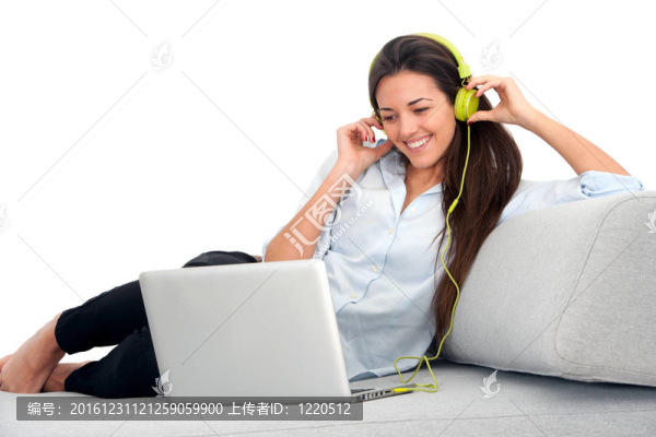 耳機(jī)和筆記本電腦在沙發(fā)上的年輕女子。