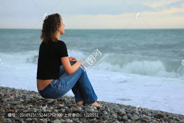 在石海岸美麗的女子坐在后面；