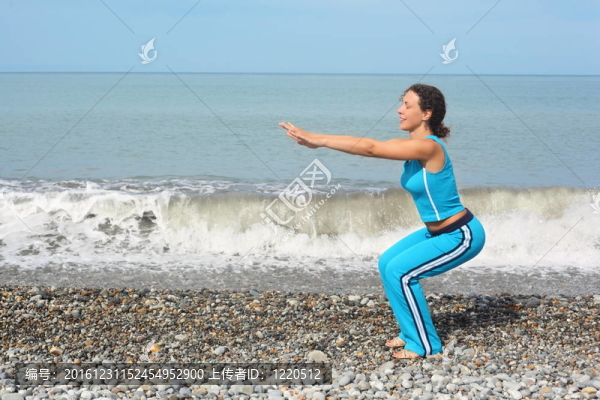 快樂(lè)的女人穿著運(yùn)動(dòng)服裝在海邊鍛煉。她蹲。
