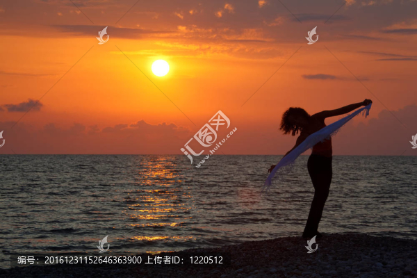海濱黃昏。日落時(shí)手上手帕的女孩剪影。