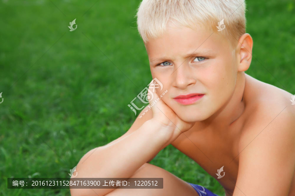 悲傷的男孩坐在草地上