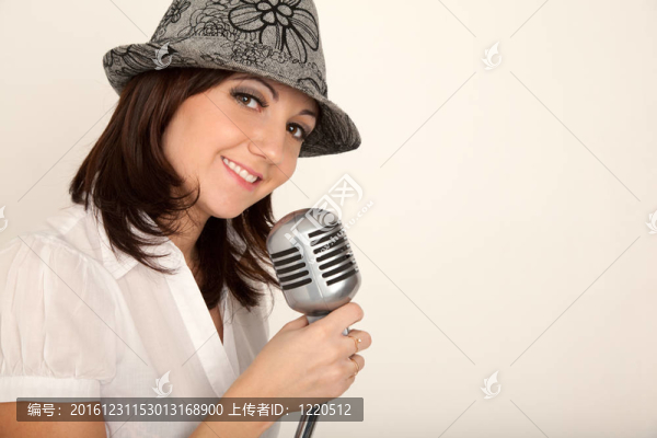 女孩穿著白色襯衫的帽子和麥克風(fēng)架在白色墻壁上的肖像。橫向格式。