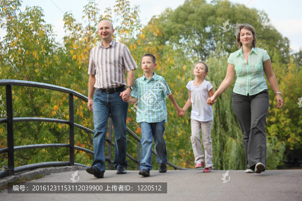 爸爸和女兒在初秋公園散步在橋上。家庭是情侶。