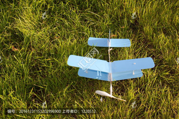 綠色草地地面上的玩具藍(lán)色飛機(jī)。前視圖