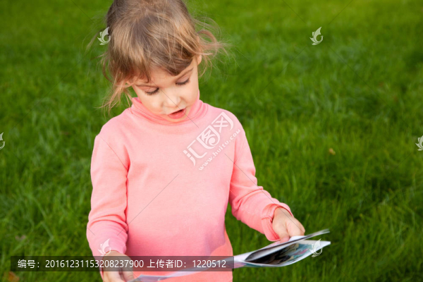 站在綠草地上的女孩。少女紅人看書故事。女孩在書中的肖像