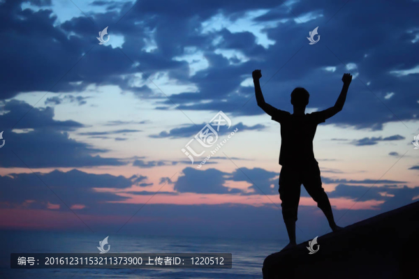 黃昏時(shí)分，人影在防波堤上向上舉起雙手