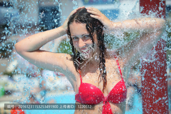 微笑的美女沐浴在池下的水濺；保持雙手放在頭后面