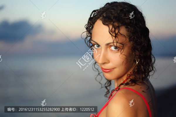 卷發(fā)的年輕漂亮的女人接近海晚；堅定不移地尋找