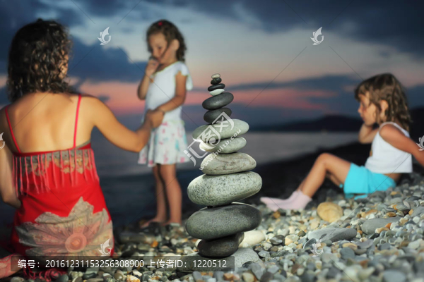 兩個小女孩，紅裙坐在金字塔從晚上石海岸卵石美麗的女人