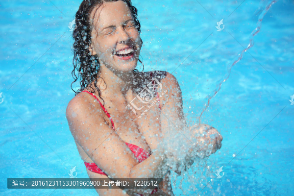 微笑的美女沐浴在池下的水濺；閉上眼睛
