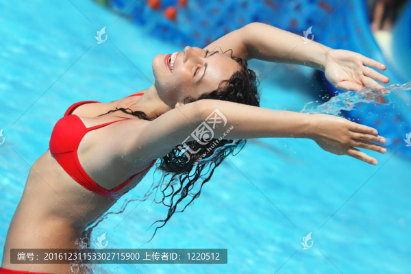 微笑的美女沐浴在池下的水流；舉起雙手向上