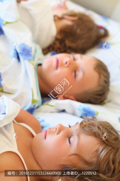 孩子三一起睡在舒適的房間床上；躺在后面