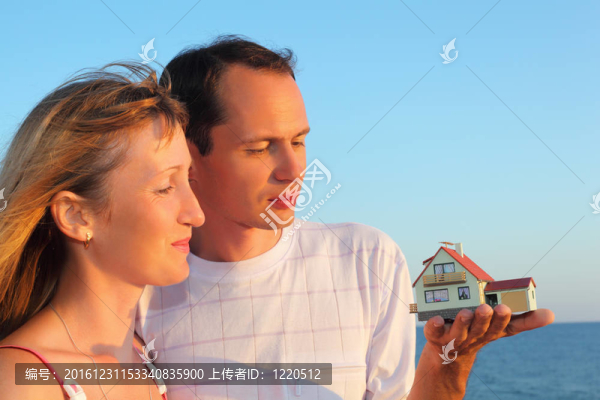 年輕女人和男人手牽手的房子模型與車庫對海在夏天
