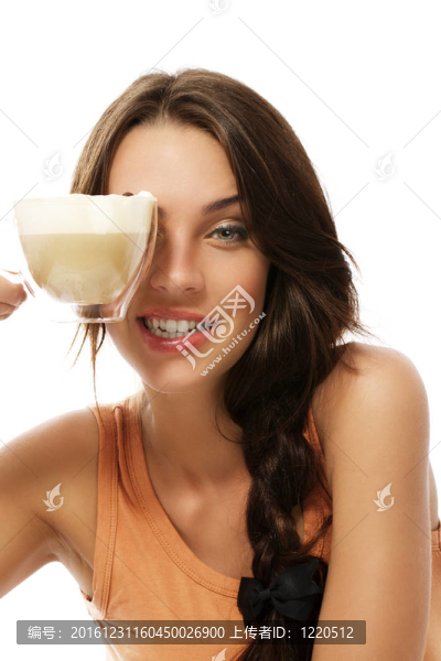 美麗的女人拿著杯卡布奇諾咖啡在她眼睛上的白色背景
