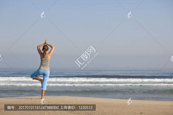 美麗的年輕女子張開雙臂，放松在海灘上