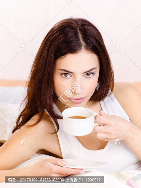 在床上抱著一杯咖啡的女人