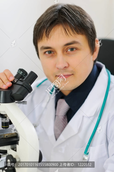 男性研究員用顯微鏡工作的畫像
