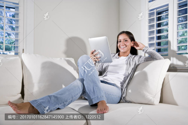 在沙發(fā)上閱讀電子書籍的西班牙裔婦女