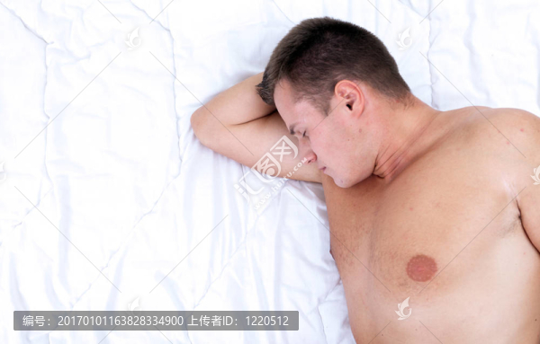 英俊的年輕人睡在白色被褥