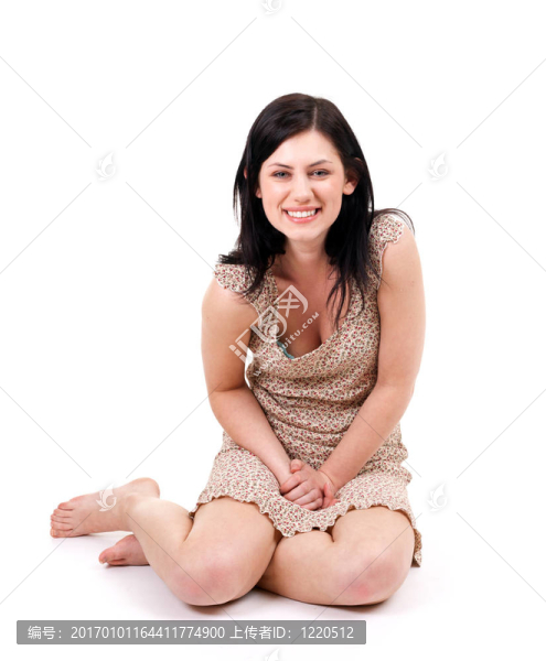 微笑的漂亮的年輕女人坐在地板上